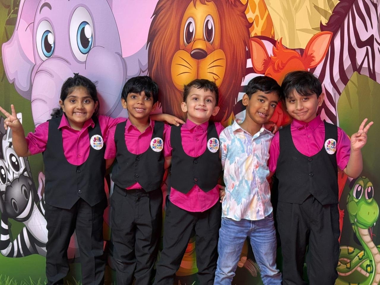 A group of Smart Minds students smiling together in front of the jungle mural